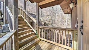 A wooden staircase leading to a covered porch with a railing, a lantern, and a view of a forested area. - Beech Mountain Cabin w/ Deck: Half-mi to Skiing (Banner Elk)