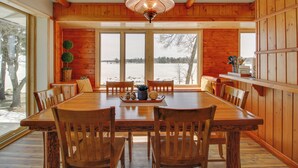 A wooden dining room with a large table and chairs, a chandelier, and a view of a snowy landscape through large windows. - 'away at Moose Bay' Breezy Point Gem w/ Game Room (Pequot Lakes)