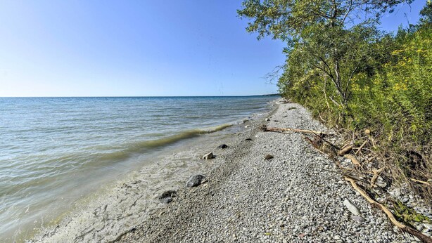 A pebbled beach with clear water and trees on the right. - Deck + Fire Pit: Waterfront Lake Michigan Escape (Algoma)