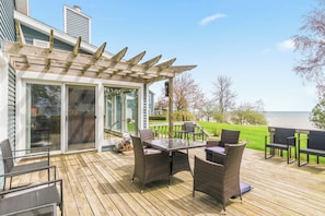 A wooden deck with outdoor furniture, a pergola, and a view of the sea. - Deck + Fire Pit: Waterfront Lake Michigan Escape (Algoma)