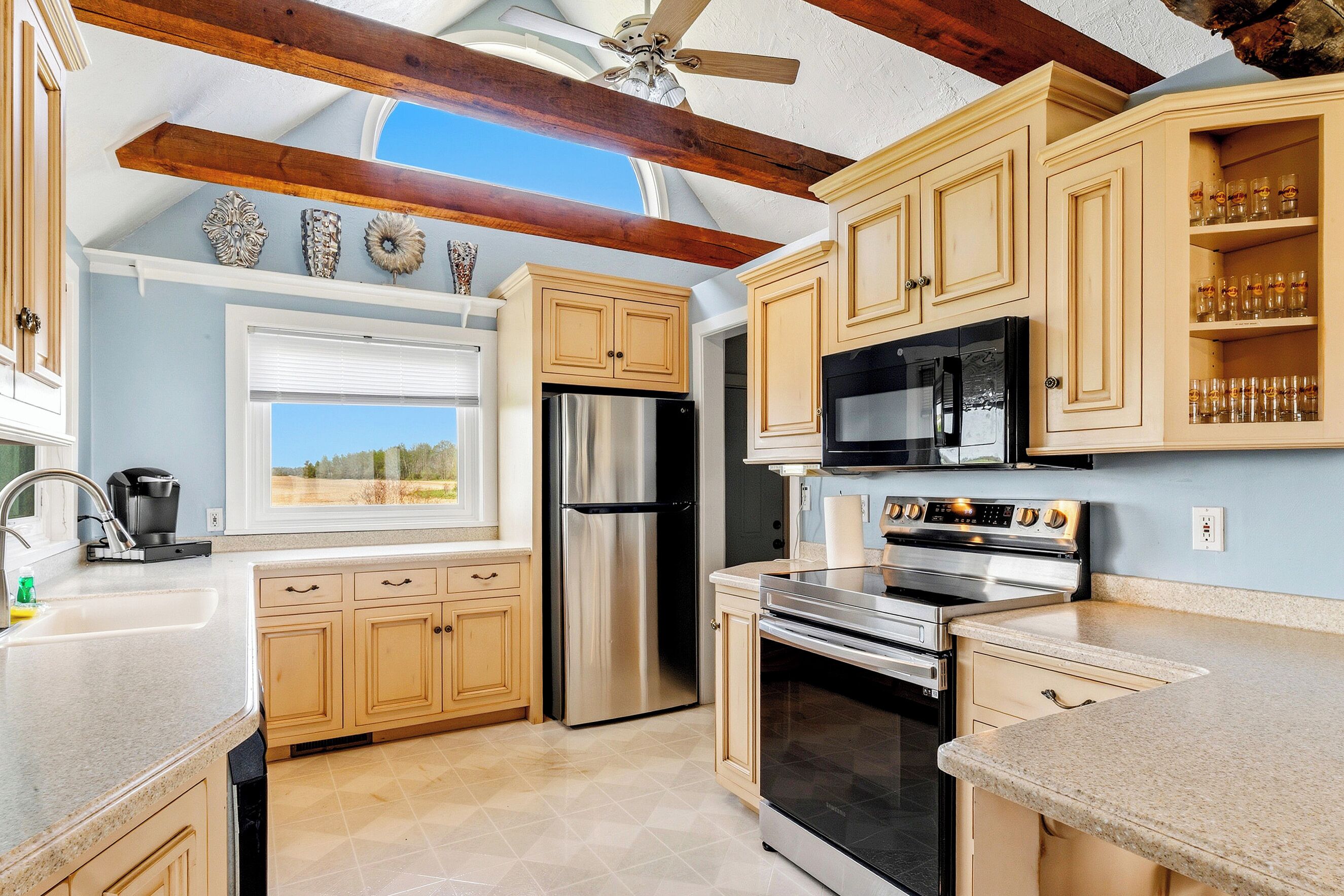 A kitchen with wooden cabinets, stainless steel appliances, and a window with a view of the outdoors.