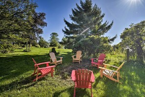 A grassy outdoor area with several Adirondack chairs arranged in a semi-circle. - Deck + Fire Pit: Waterfront Lake Michigan Escape (Algoma)