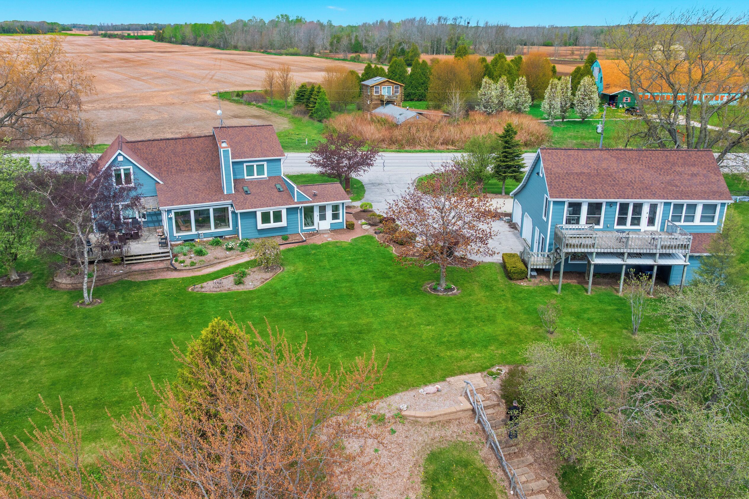 A residential area with two main houses, a barn, and a train track.