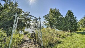 A pathway leading through a natural setting with a metal gate and trees. - Deck + Fire Pit: Waterfront Lake Michigan Escape (Algoma)