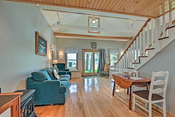 A spacious living area with a wooden floor, a sofa, a dining table with chairs, and a staircase.