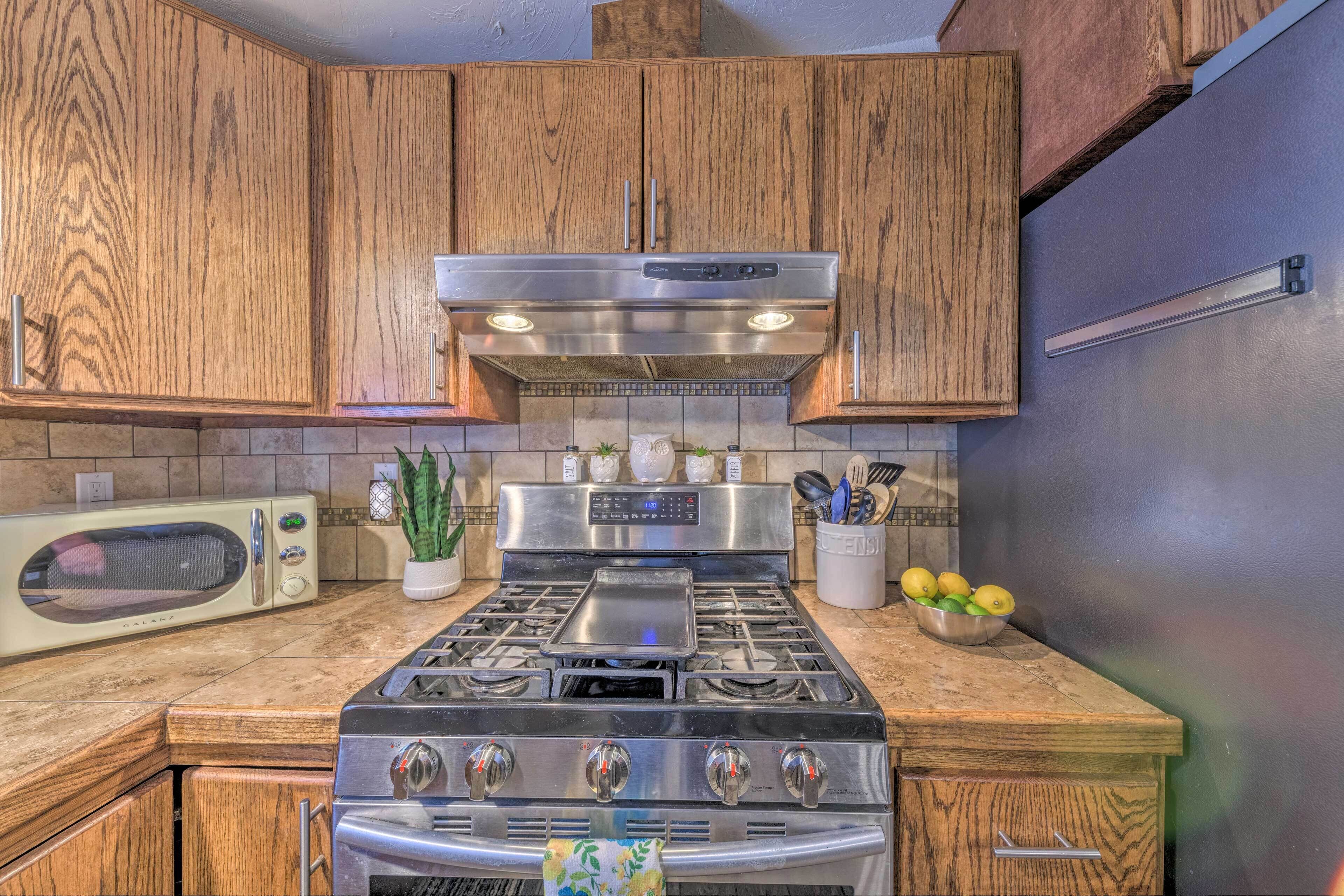 A kitchen with wooden cabinets, a stainless steel stove, a microwave, and a refrigerator.
