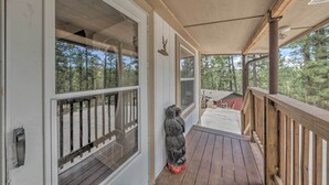 Une terrasse en bois avec une balustrade, de grandes fenêtres et une statue d’ours.