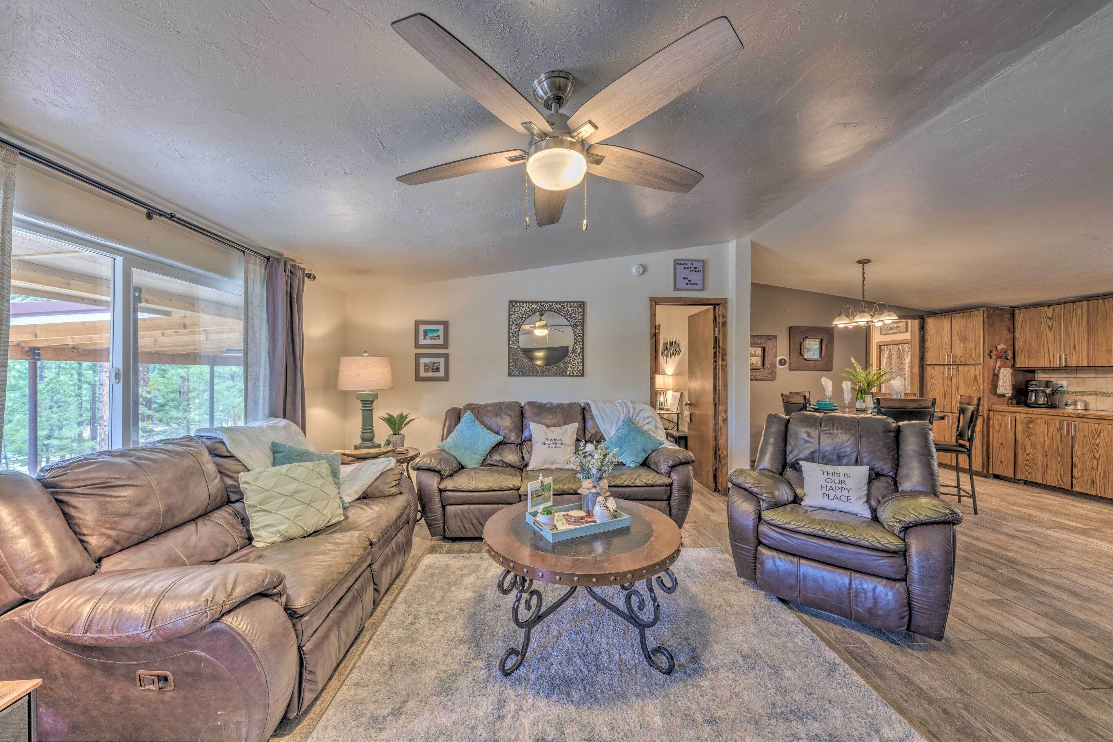 A spacious living room with leather sofas, a central coffee table, and a ceiling fan.