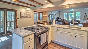 A spacious kitchen with a large island, wooden beams, and a view of a living area with a fireplace. - Hot Tub, Beach Access: Albrightsville Retreat! (Albrightsville)