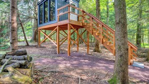 A wooden treehouse with a staircase, surrounded by a forest. - Hot Tub, Beach Access: Albrightsville Retreat! (Albrightsville)