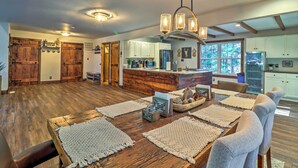 A spacious kitchen with wooden cabinets, a central island, and a dining area with a large wooden table and chairs. - Hot Tub, Beach Access: Albrightsville Retreat! (Albrightsville)