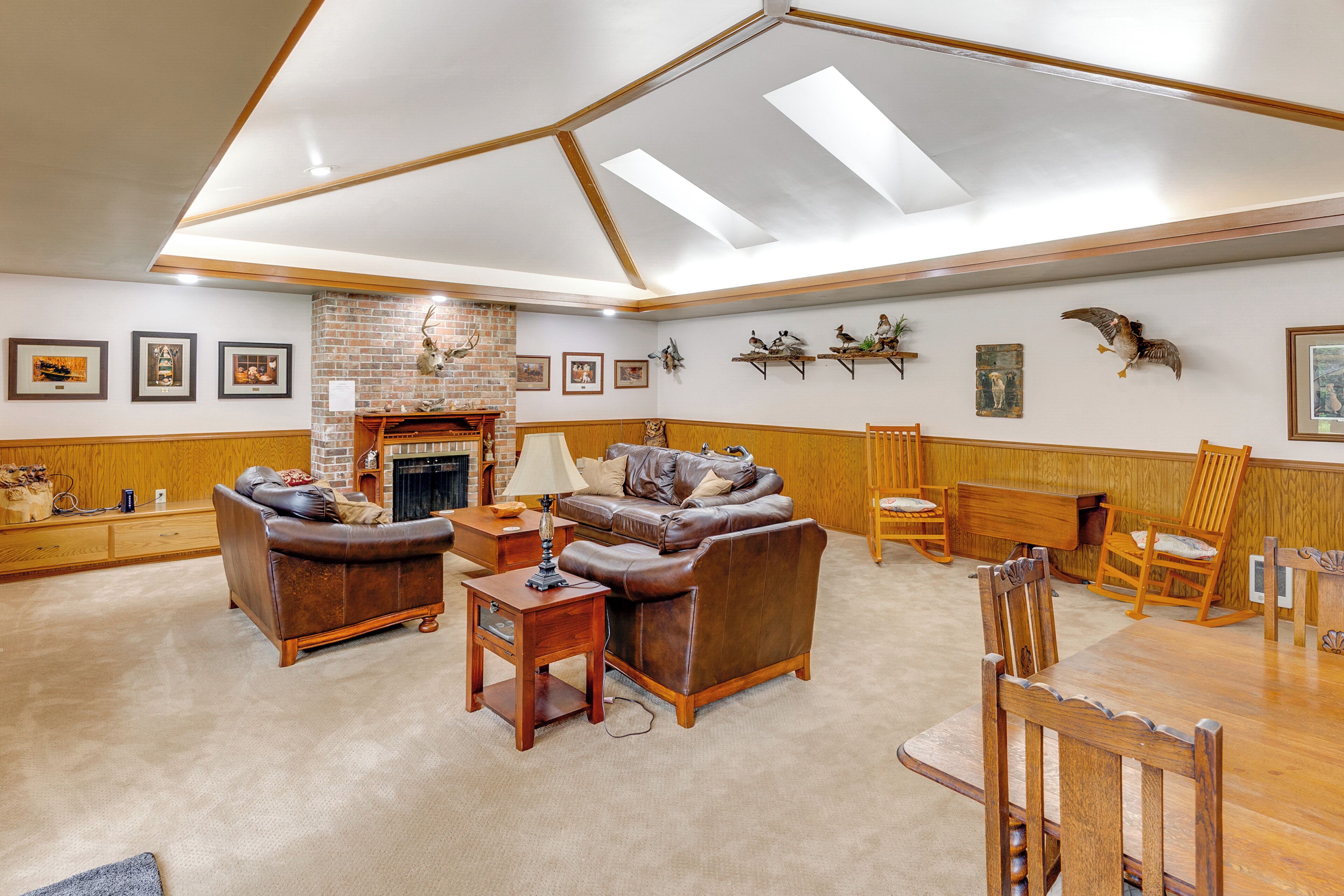 A spacious living room with a fireplace, leather sofas, wooden furniture, and wall-mounted decorations.