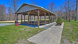 A covered picnic area with benches and a trash can.