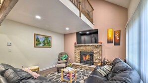 A living room with a fireplace, a sofa, a chair, and a painting on the wall.