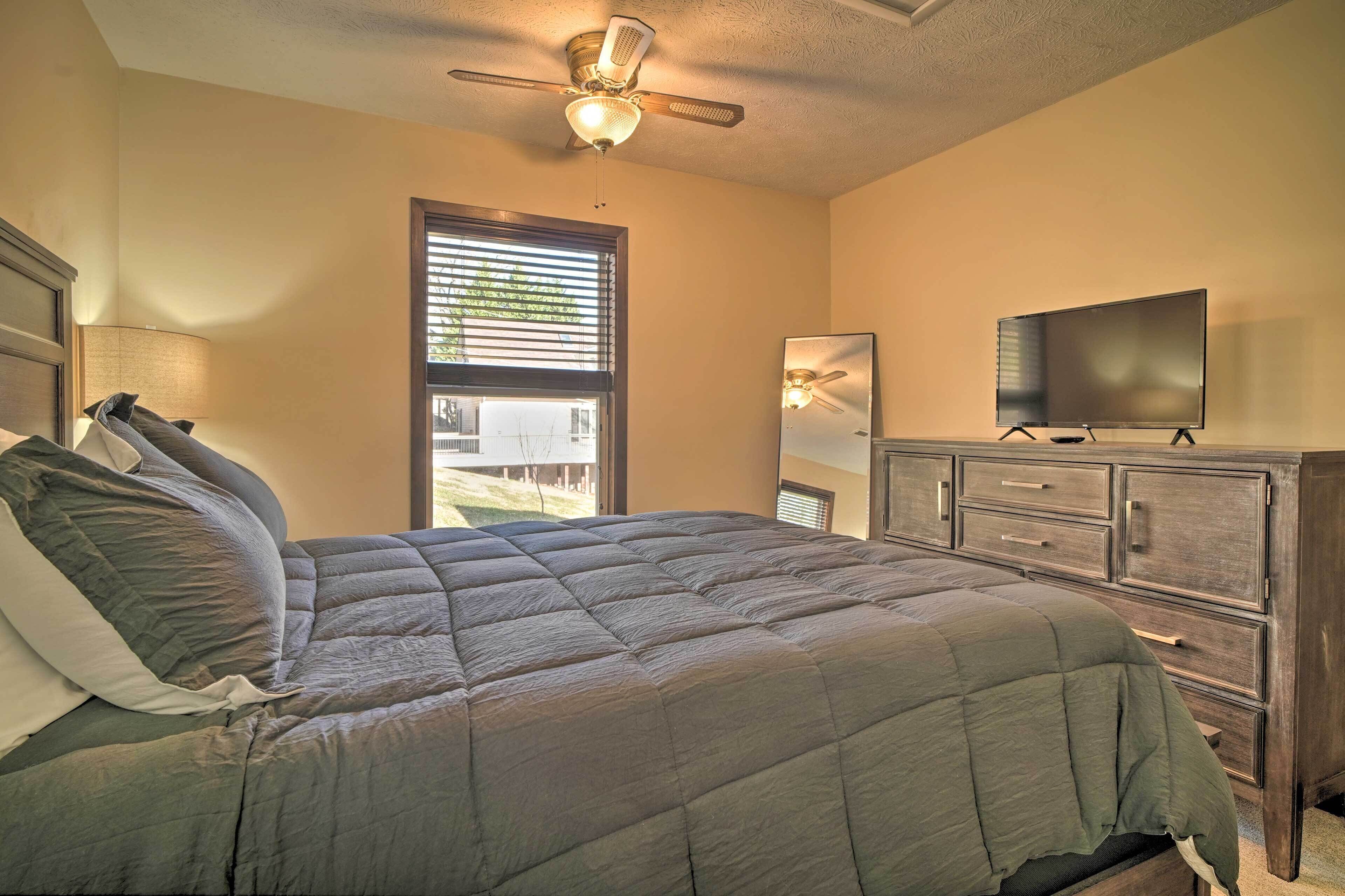 Ein Schlafzimmer mit Bett, Fernseher, Kommode und Deckenventilator.
