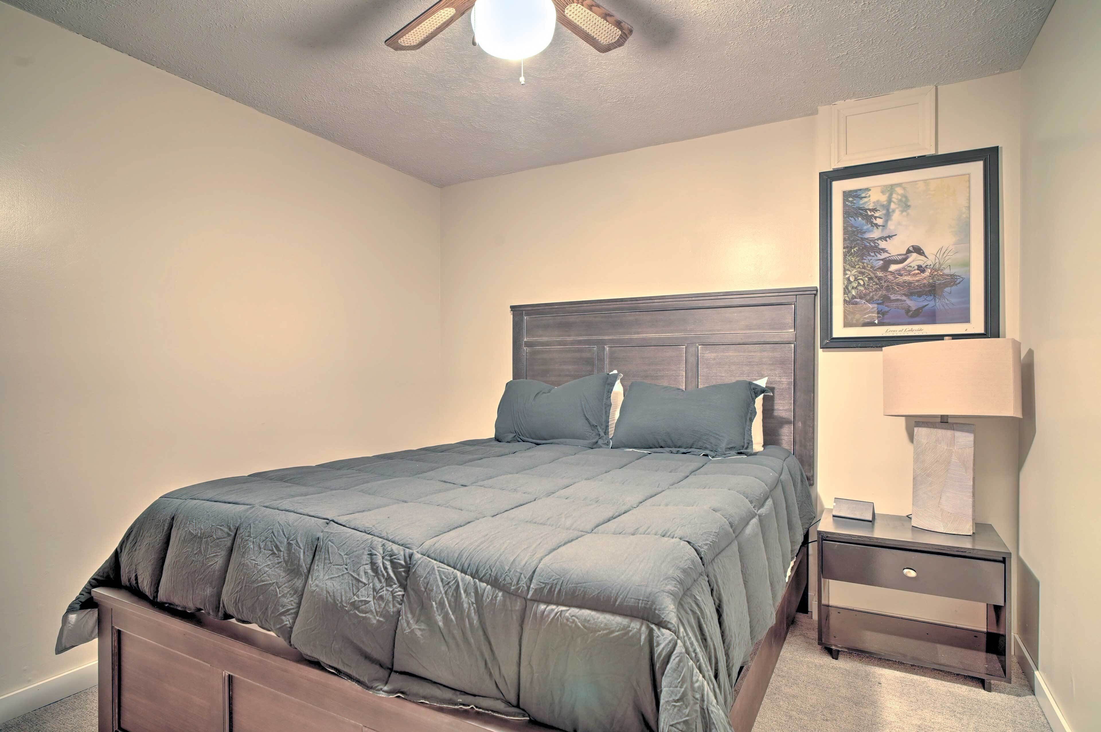 A bedroom with a bed, nightstand, lamp, and a framed picture on the wall.