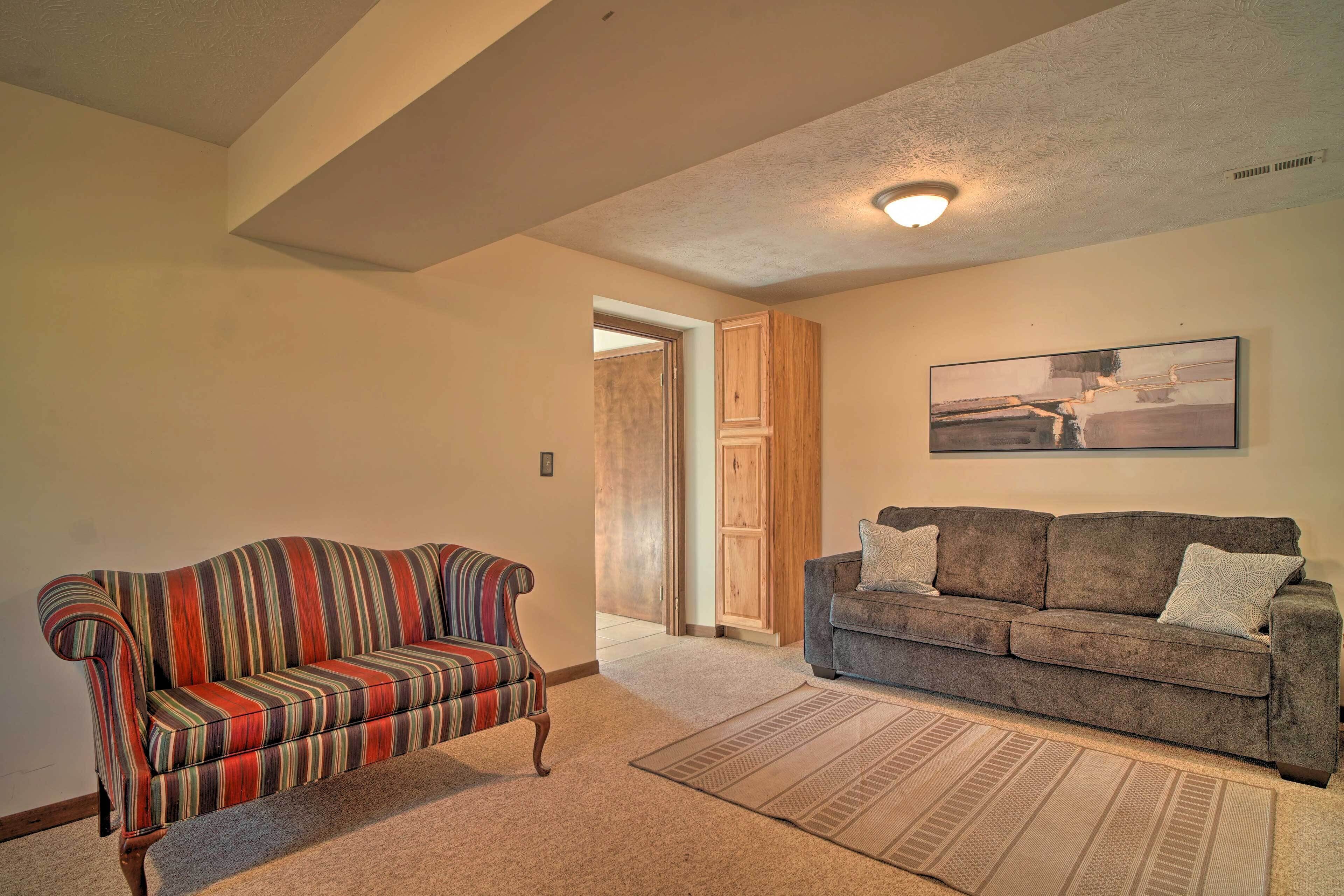 A living room with two sofas, a patterned rug, and a painting on the wall.