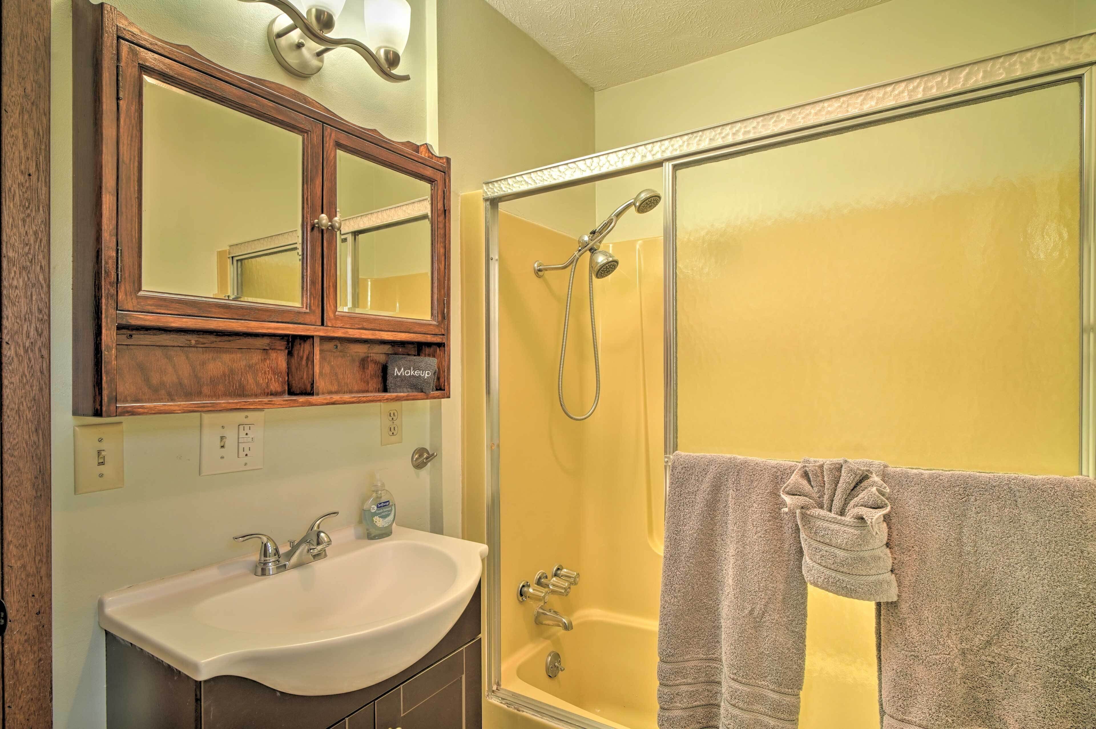 A bathroom with a wooden vanity, a sink, a mirror, and a glass-enclosed shower.