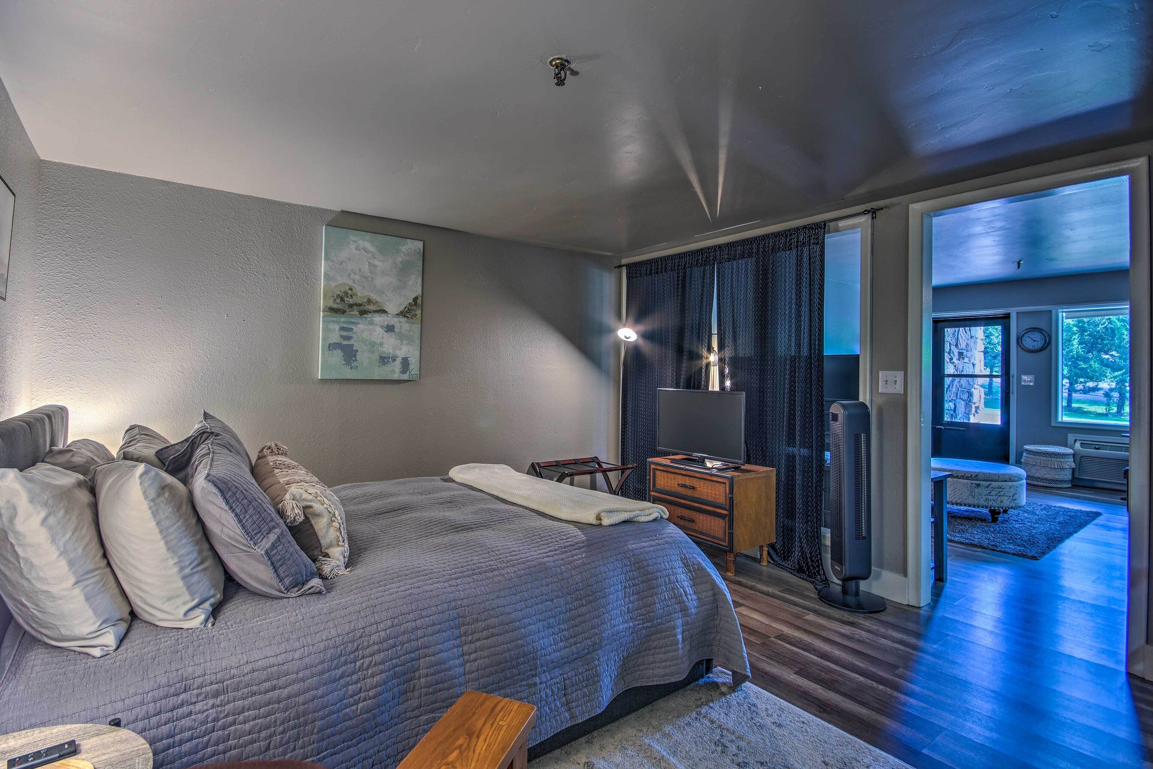 Une chambre avec un grand lit, une table de chevet, une télévision et une vue sur l’extérieur.