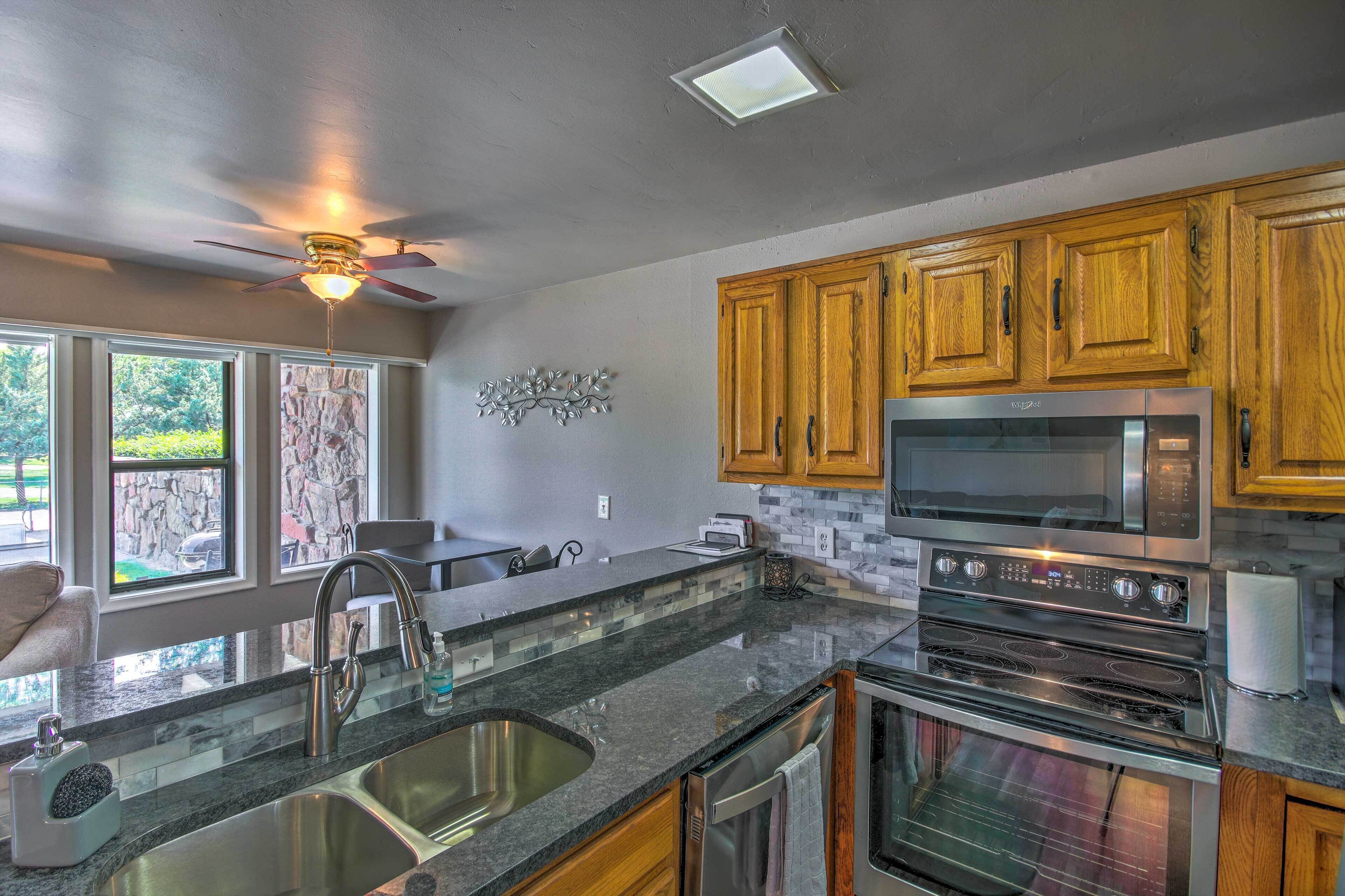 A modern kitchen with granite countertops, stainless steel appliances, wooden cabinets, and a built-in oven.