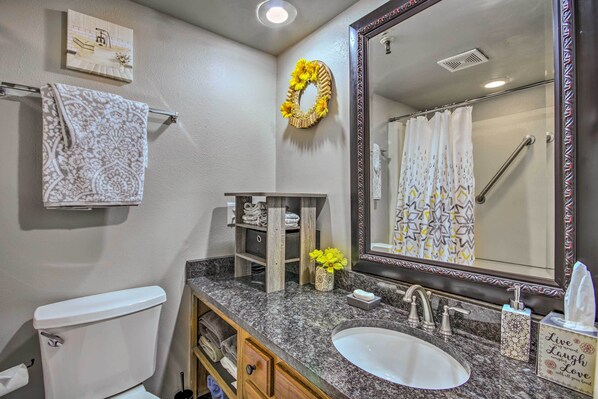 A bathroom with a toilet, sink, mirror, towel rack, and shower curtain. - Pool Access: Condo w/ Patio in Afton (Afton)
