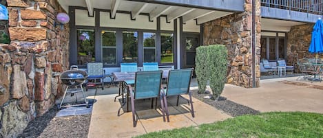 Un edificio de piedra con un patio cubierto, mobiliario exterior y una parrilla.