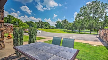 A patio with a stone table and chairs, overlooking a road and a golf course.