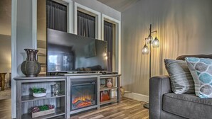 Ein modernes Wohnzimmer mit Kamin, großem Flachbildfernseher und grauem Sofa.