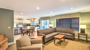 A living room with a sofa, armchairs, a coffee table, and a dining area with chairs and a table.