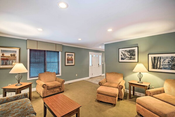 A living room with beige carpet, two armchairs, a wooden coffee table, and two lamps.