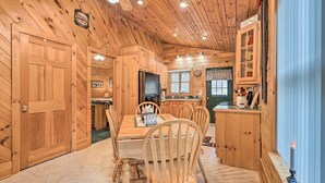 Een houten cabin met een eethoek, keuken en een gezellige open haard.