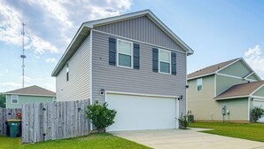 A two-story residential building with a garage, a wooden fence, and a clear sky. - 'camden Ocean Springs' House Near Beaches! (Ocean Springs)