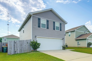 A two-story residential building with a garage, a wooden fence, and a clear sky. - 'camden Ocean Springs' House Near Beaches! (Ocean Springs)
