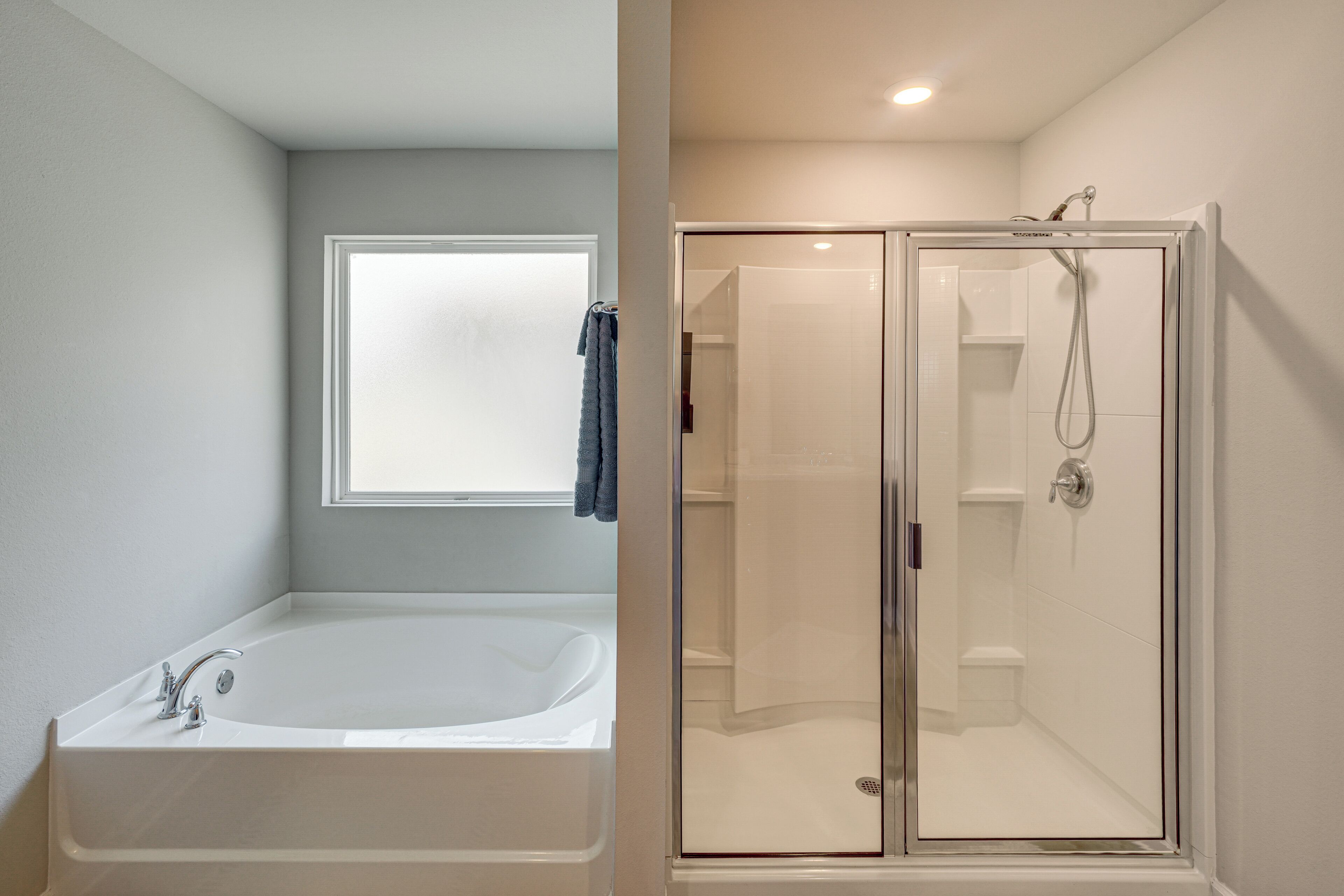 A bathroom with a bathtub, a shower, and a window.