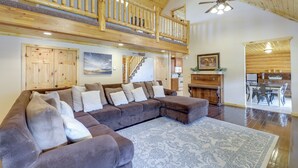 A spacious living area with a large sectional sofa, a wooden ceiling, and a view of the kitchen. - Large Sterling Cabin < 1 Mi to Palisade State Park (Sterling)