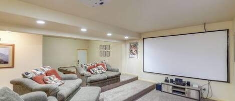 A home theater room with a large screen, comfortable seating, and a projector.