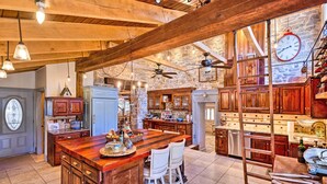 A spacious kitchen with a large island, wooden cabinets, and a stone wall.