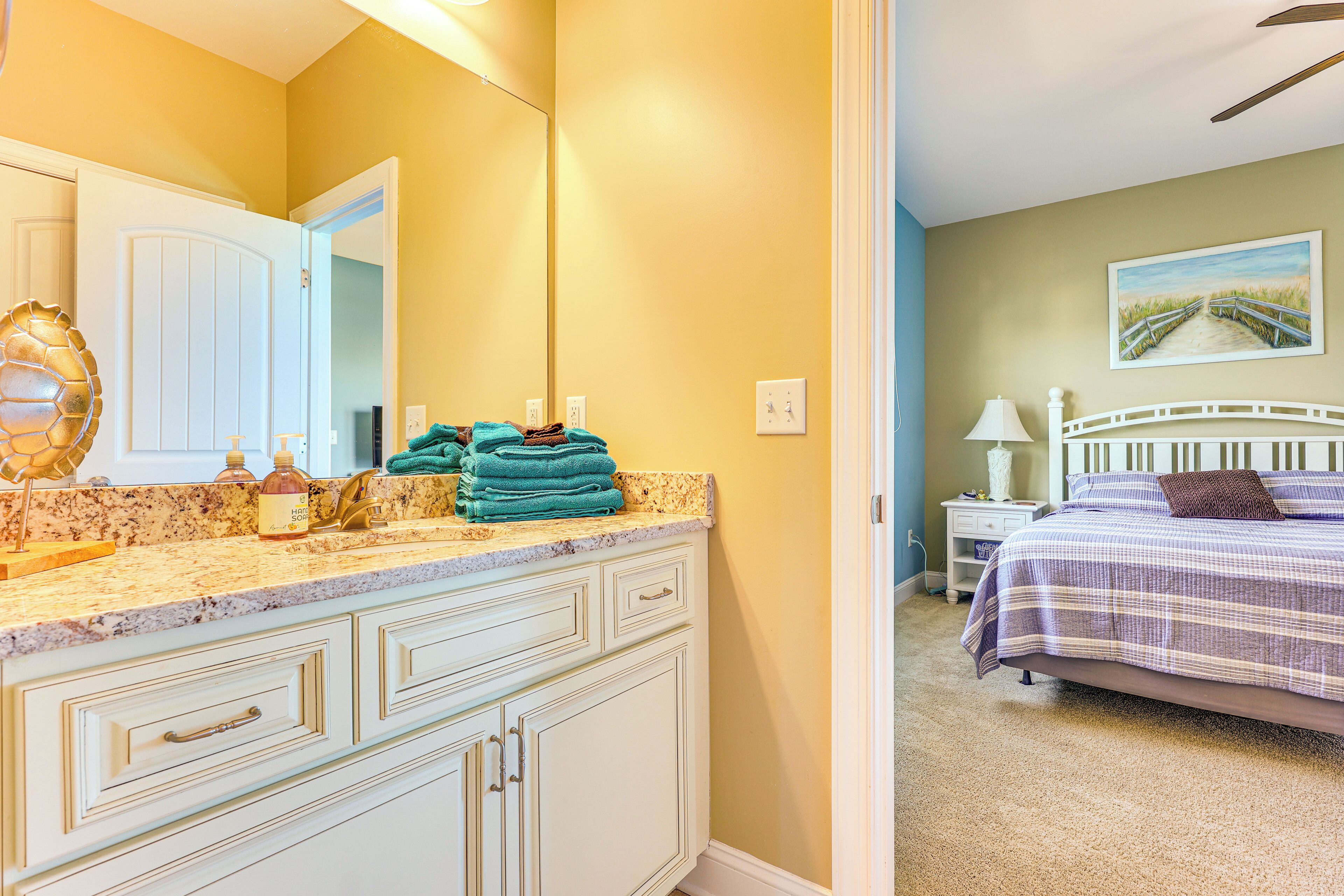 A bathroom with a white vanity, a large mirror, and a towel rack.