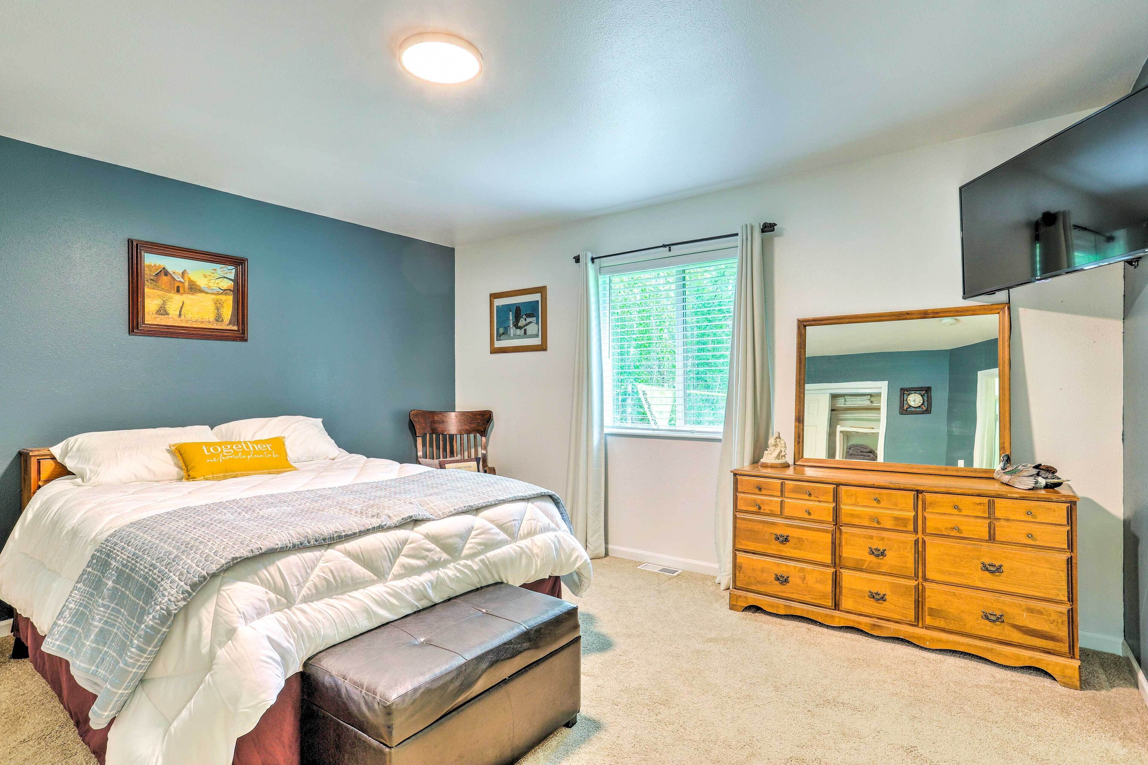 Une chambre à coucher avec un lit, une commode, un miroir et deux tableaux encadrés accrochés au mur.