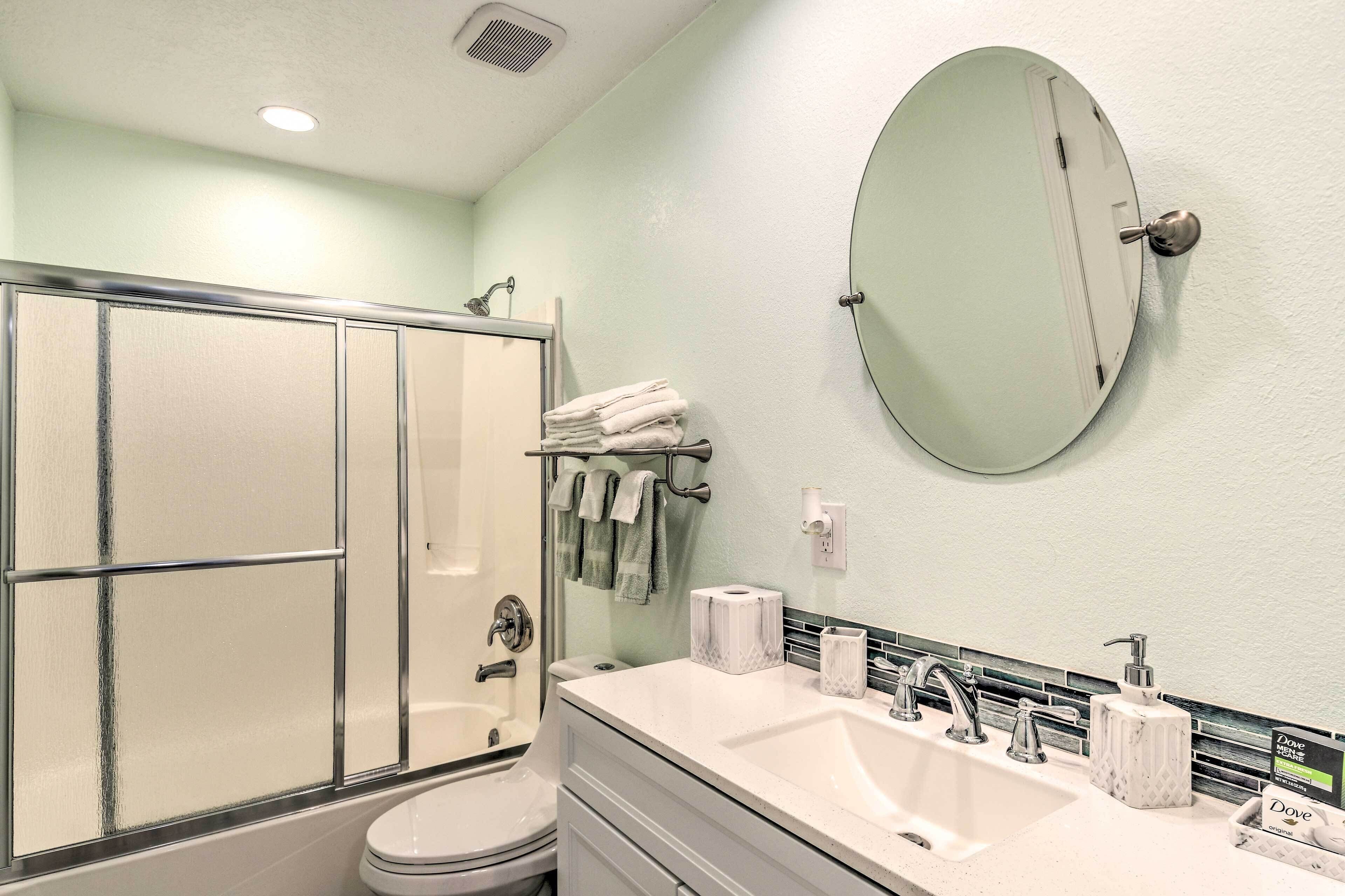 Ein Badezimmer mit Dusche, Toilette, Waschbecken und Spiegel.