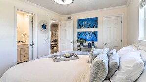 Un dormitorio con una cama grande, un ventilador de techo y obras de arte en la pared.