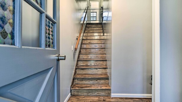 A wooden staircase leading to a landing with a glass door and a view of the outside. - 14 Mi to Frankenmuth: Apt on 3 Acres in Clio! (Clio)