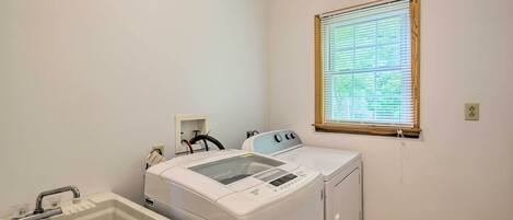 Un espace buanderie comprenant un lave-linge, un sèche-linge et un évier.