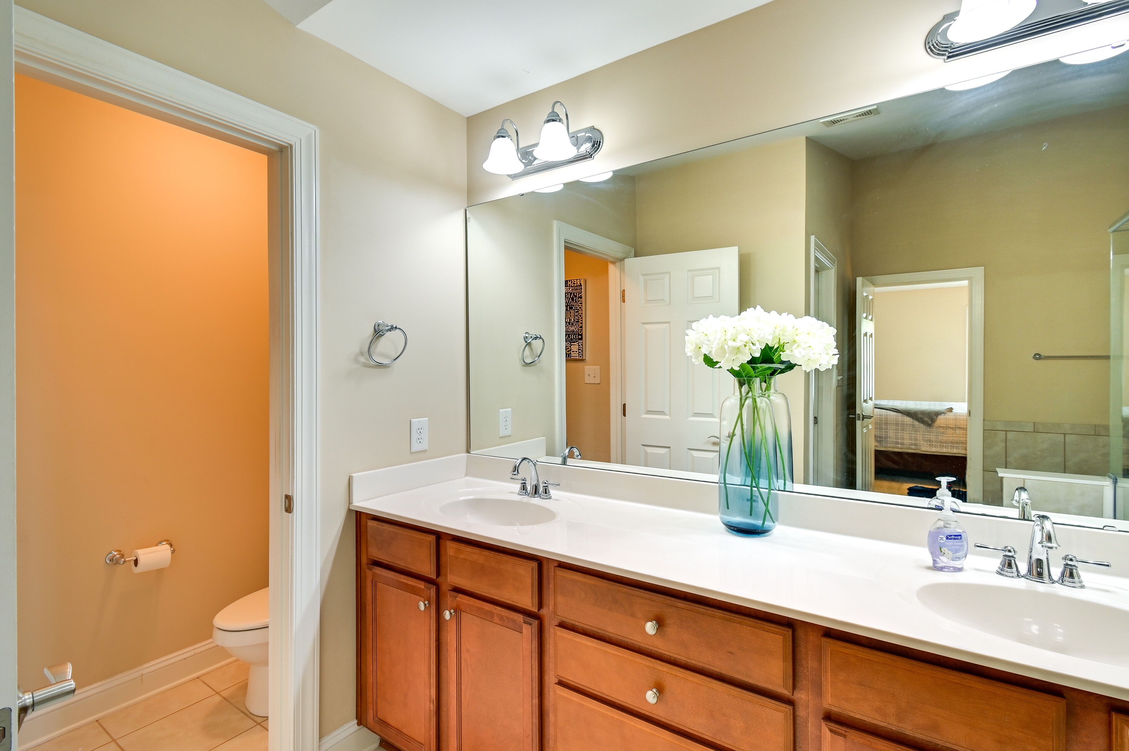 A bathroom with a white sink, wooden vanity, and a large mirror.