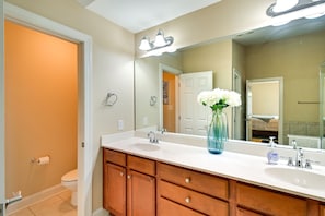 Une salle de bain avec un lavabo blanc, un meuble-lavabo en bois et un grand miroir.