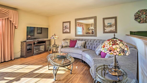 Een woonkamer met een televisie, bank en glazen salontafel.
