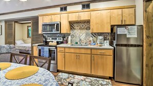 A compact kitchen with wooden cabinets, a stainless steel refrigerator, a microwave, and a stove. - Coos Bay Cottage w/ Fireplace & BBQ Patio! (Coos Bay)