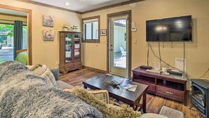 A cozy living room with a sofa, a coffee table, a TV, and a fireplace. - Coos Bay Cottage w/ Fireplace & BBQ Patio! (Coos Bay)