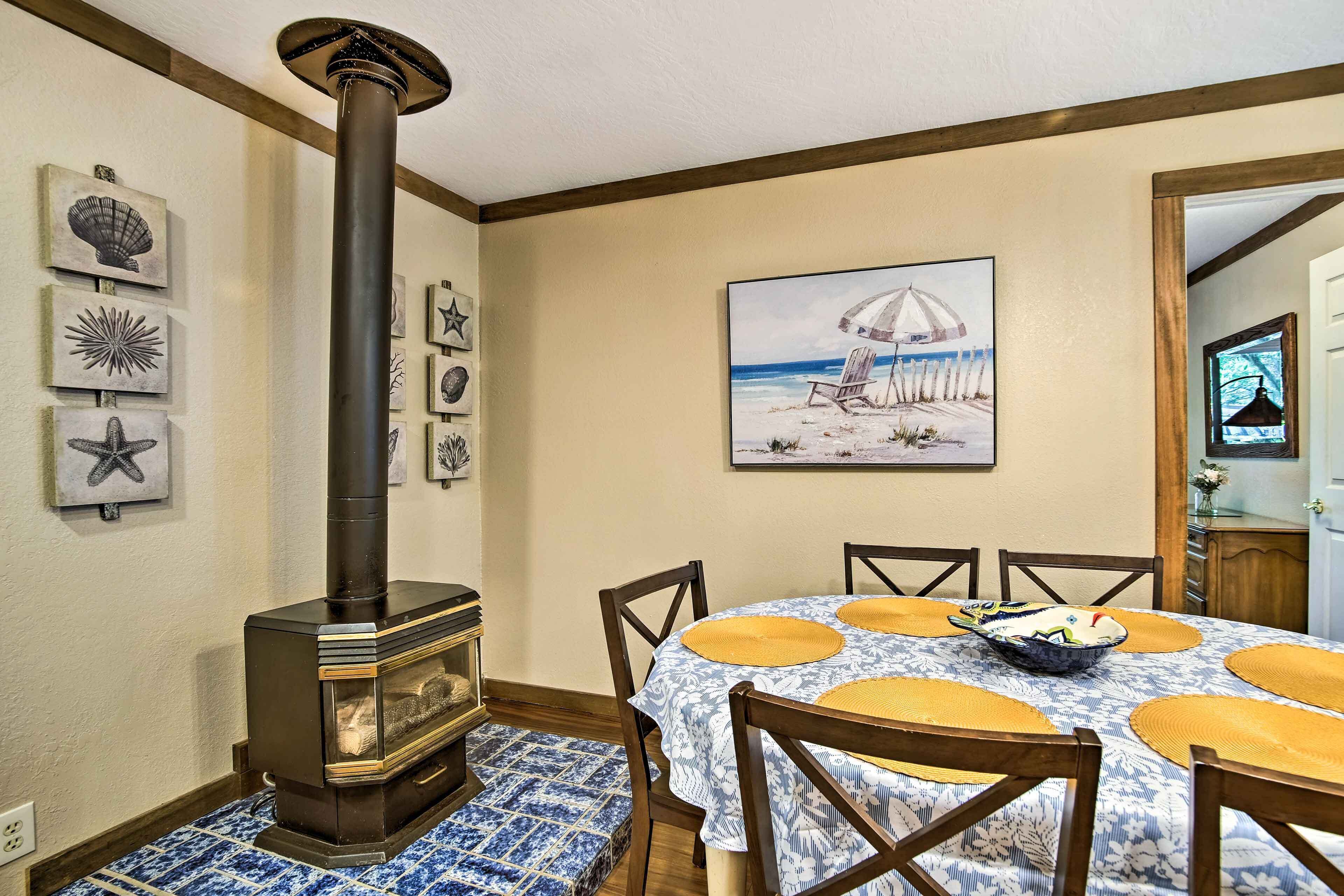 Un comedor con estufa de leña, un cuadro con temática marina y decoraciones de estrellas de mar en la pared.