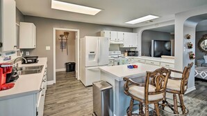 A modern kitchen with white cabinets, a central island with bar stools, and a large refrigerator. - Dog-friendly Texas Retreat w/ Hot Tub, Patio & Bar (Converse)